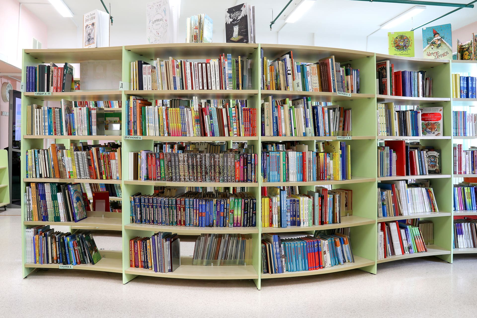 Название стеллажей. Стол для читального зала. Название стеллажей в библиотеке. Оформление читального зала библиотеки. Книжные полки в младшей школе.